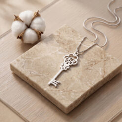 Collier Clé avec Initiales en argent 925 posé sur une surface en marbre beige
