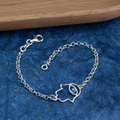 Bracelet Hamsa œil bleu en argent sterling posé sur une surface en velours bleu