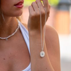 Collier soleil œil bleu tenu dans la main