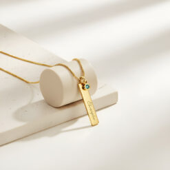 magnifique Collier Barre Gravée avec Charm Pierre de Naissance en plaqué or posé sur un beau support cylindrique