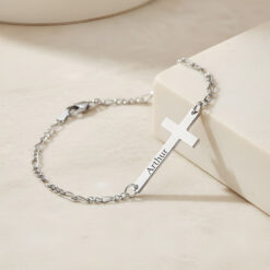 Bracelet Croix Gravée pour Homme en argent 925 posé sur une belle surface beige.