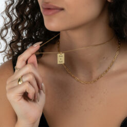 Femme portant un collier plaque personnalisé en acier inoxydable doré, style minimaliste et élégant pour le quotidien.
