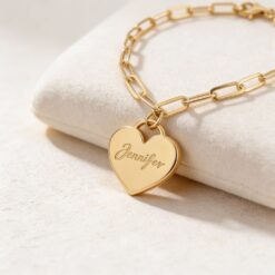 Bracelet cœur personnalisé posé sur un support beige.