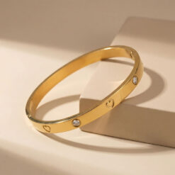 Bracelet Jonc Cœurs et Zirconium en Acier Doré posé sur une belle surface beige matte
