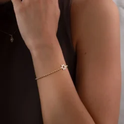 Bracelet étoile de David en plaqué or porté au poignet sur une peau halée. Design minimalist. Cadeau féminin qui saura faire plaisir.